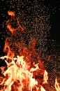 Vivid orange flames and sparks dance against a mysterious black backdrop.