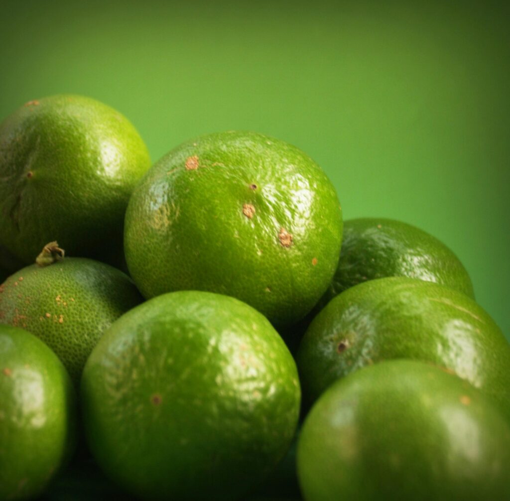 A close-up of fresh limes on a vibrant green background, capturing their juicy and natural essence.